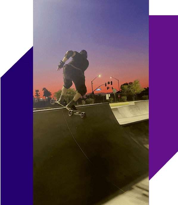 Skateboarder performing trick at sunset skatepark.
