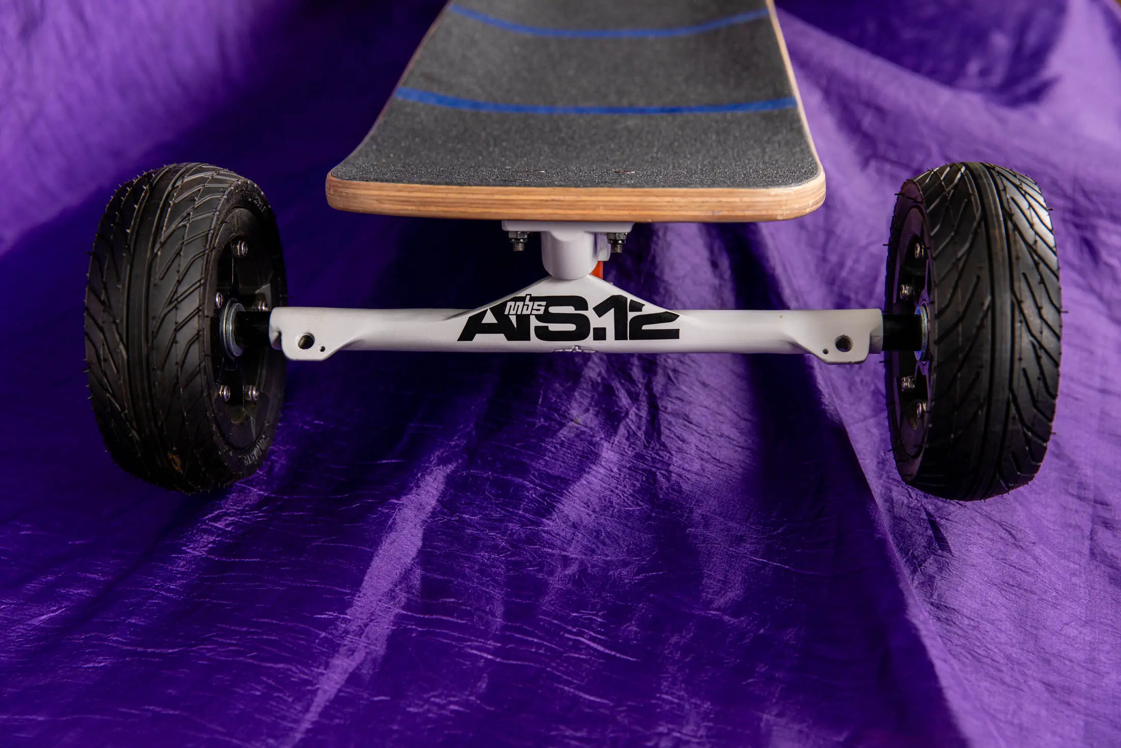 Skateboard with large wheels on purple fabric.