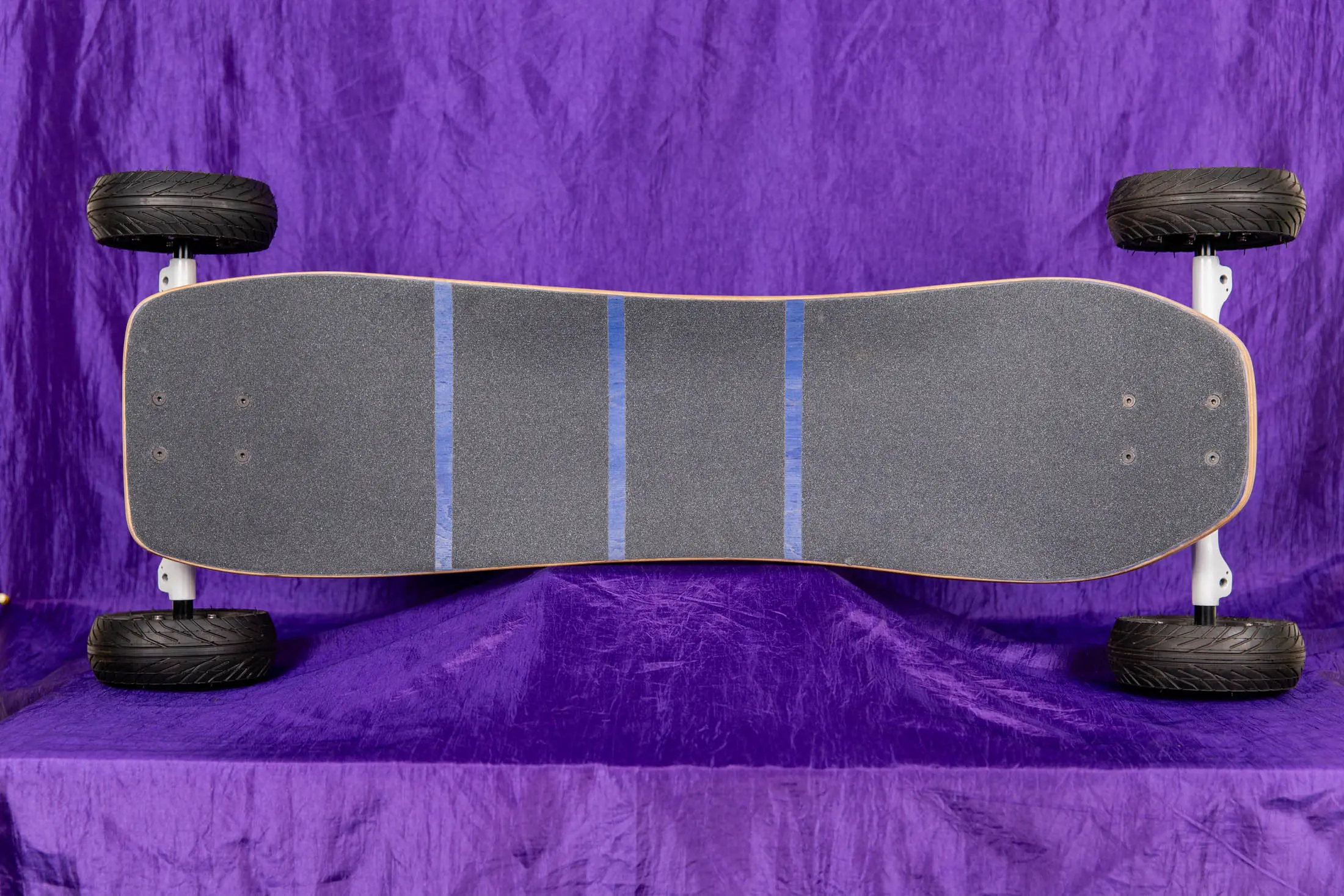 Off-road skateboard on purple fabric background.