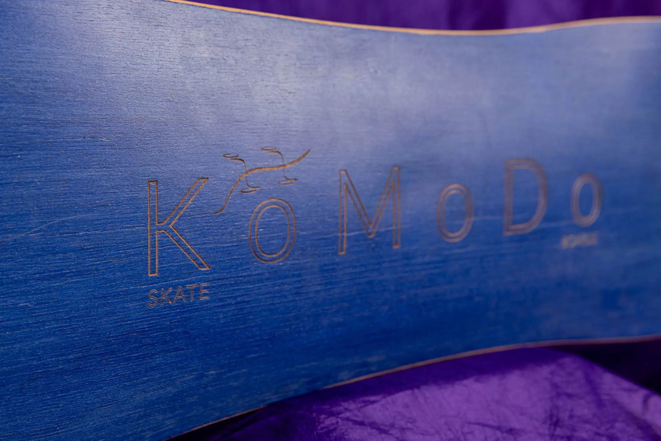 Blue skateboard with "KoMoDo" engraved text.