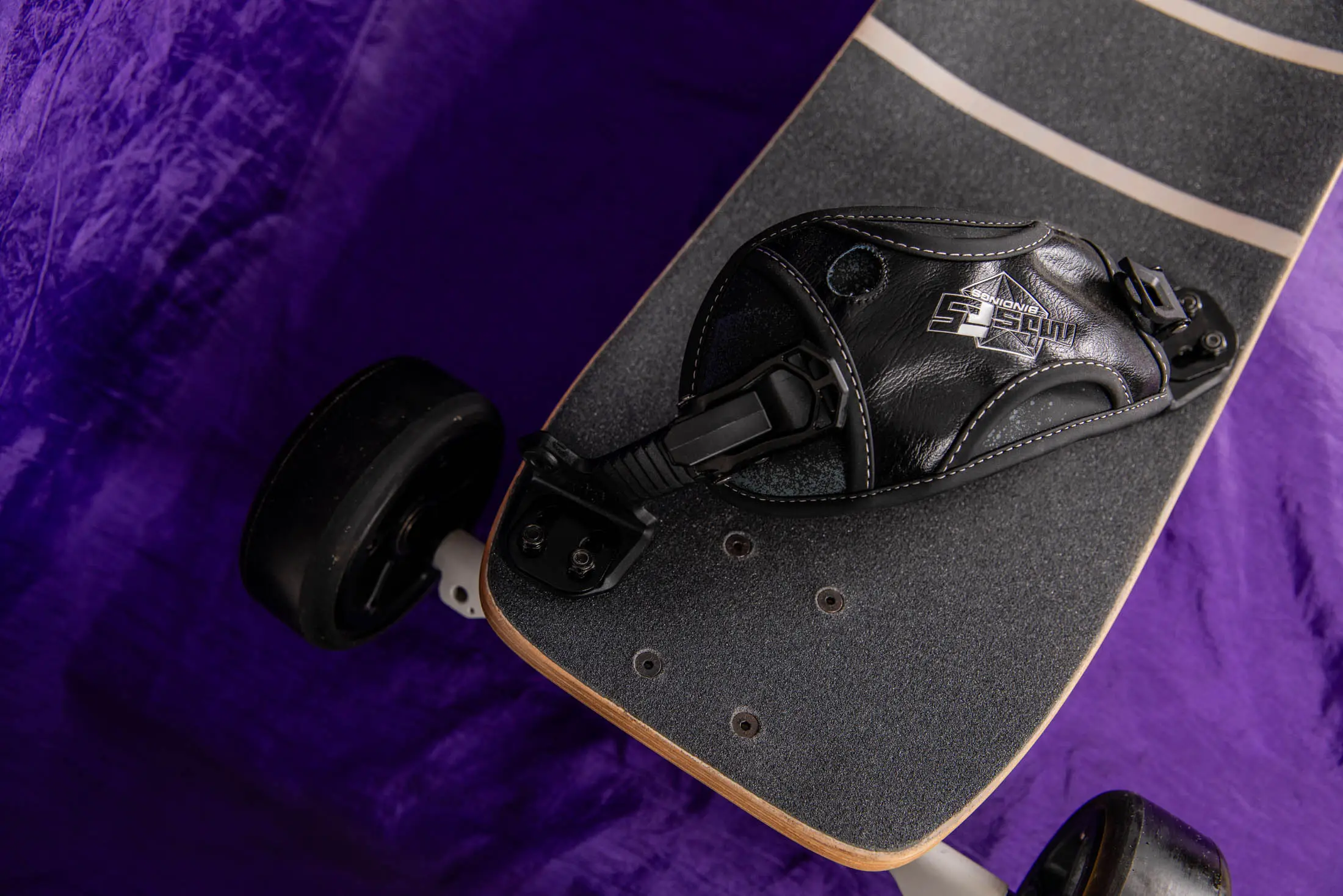 Electric skateboard with foot strap on purple.