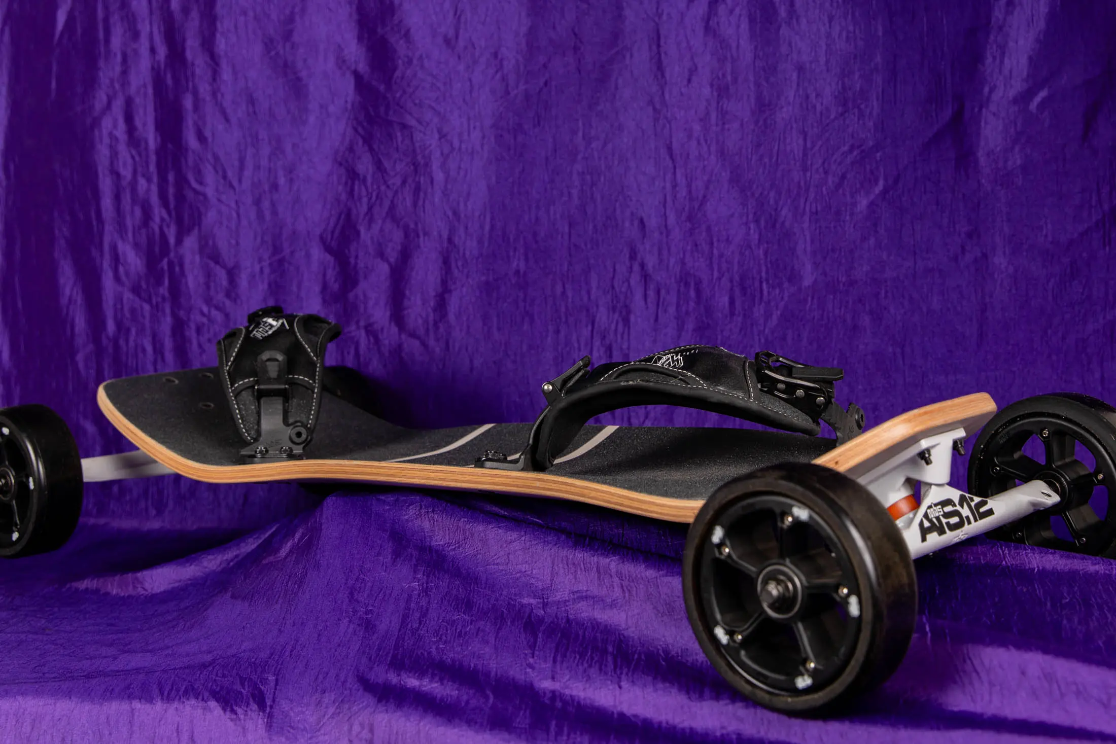 Off-road skateboard on purple fabric background.