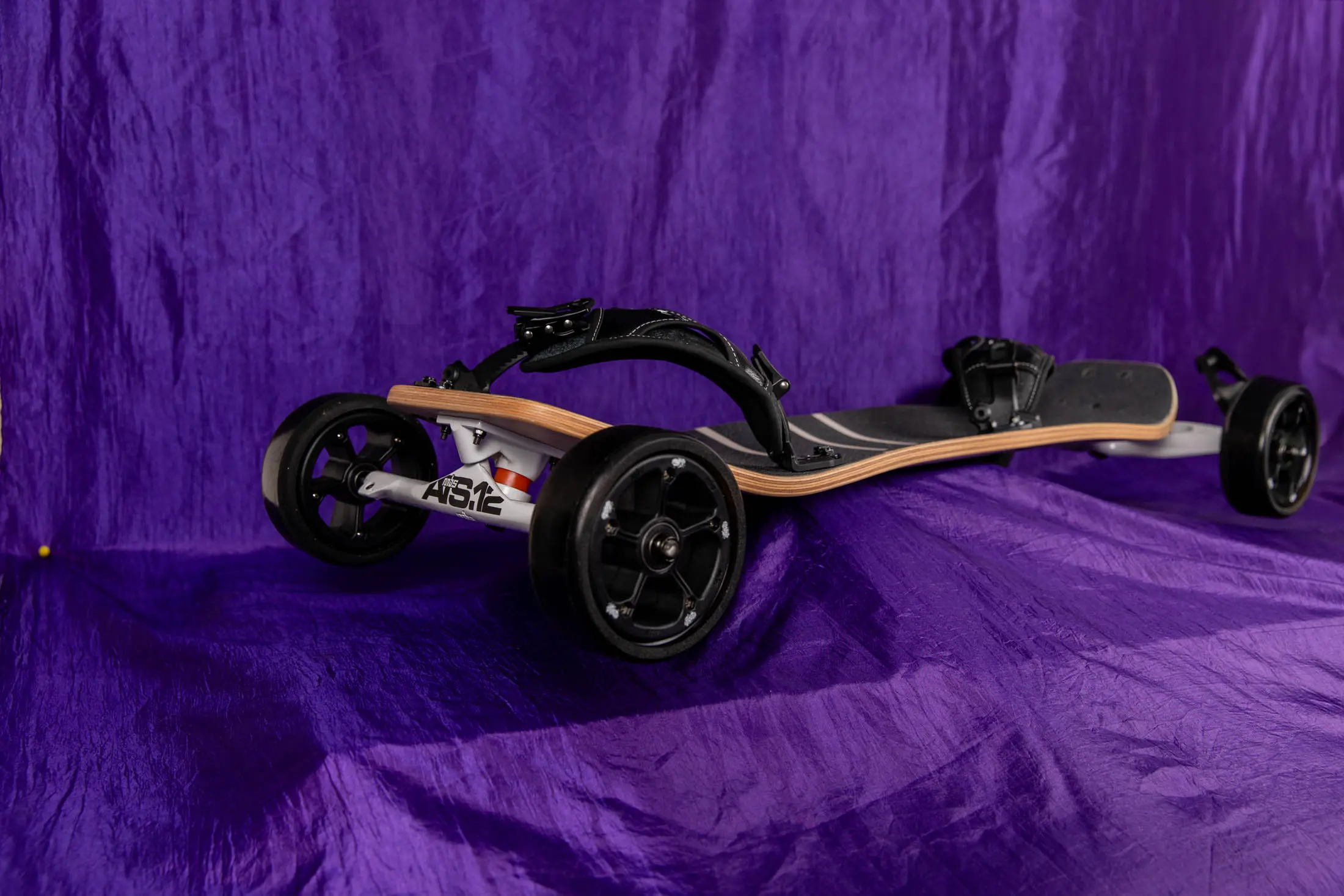 All-terrain skateboard on purple fabric background.