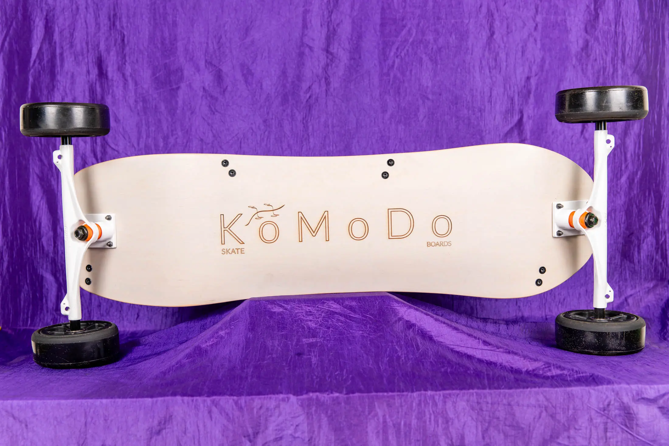 Electric skateboard on purple fabric background.