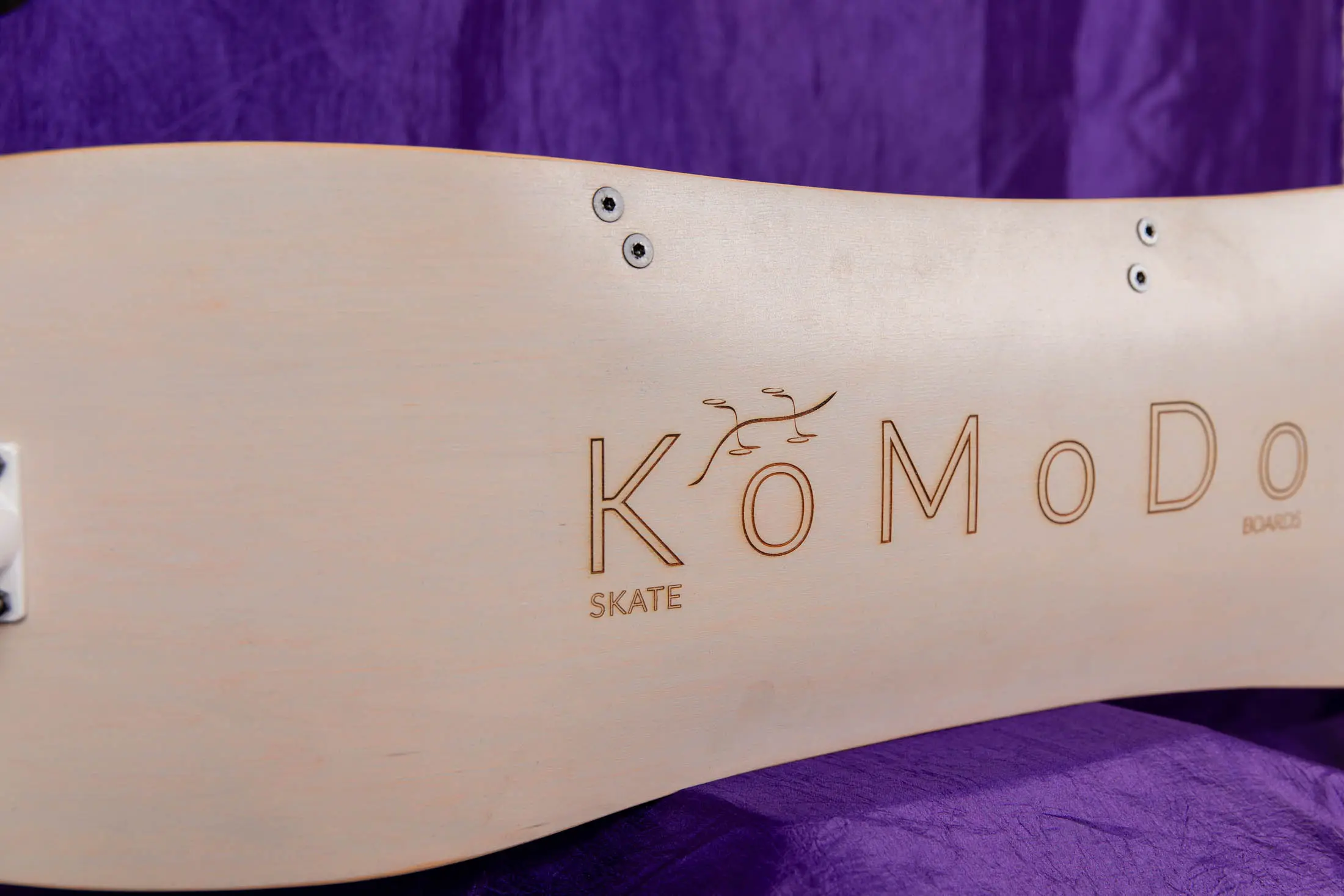 Wooden skateboard with "KoMoDo" logo on it.