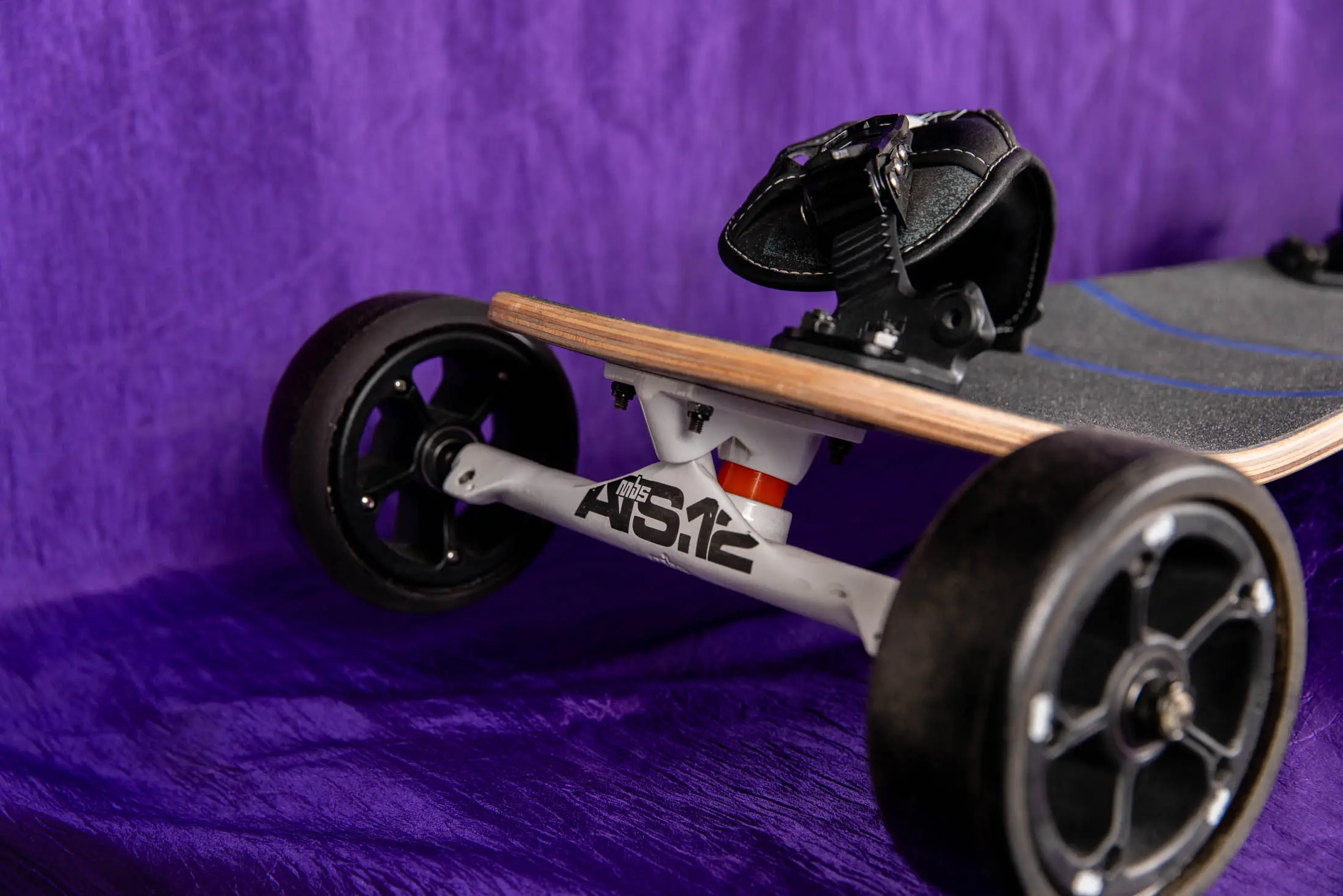 Electric skateboard on purple fabric background.