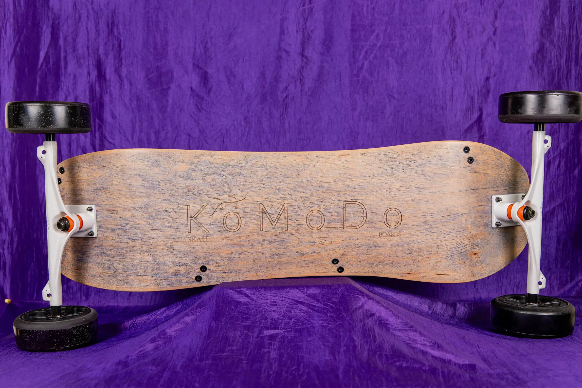 Wooden skateboard on purple fabric background.