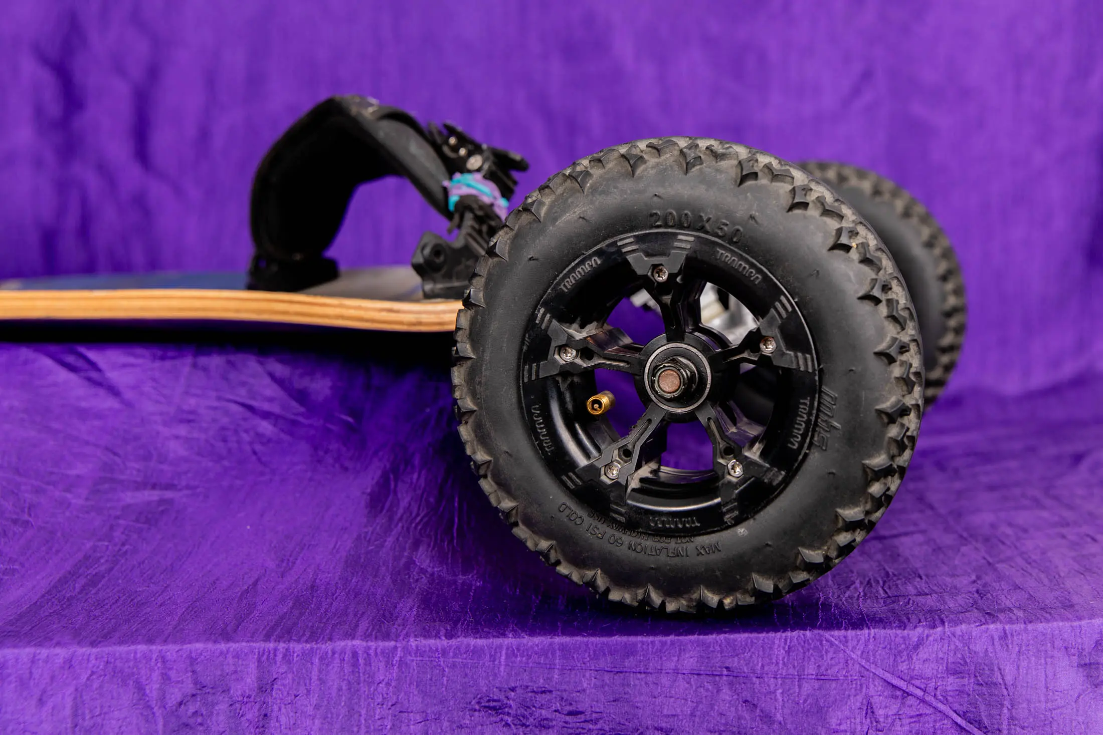 All-terrain skateboard wheel on purple background.