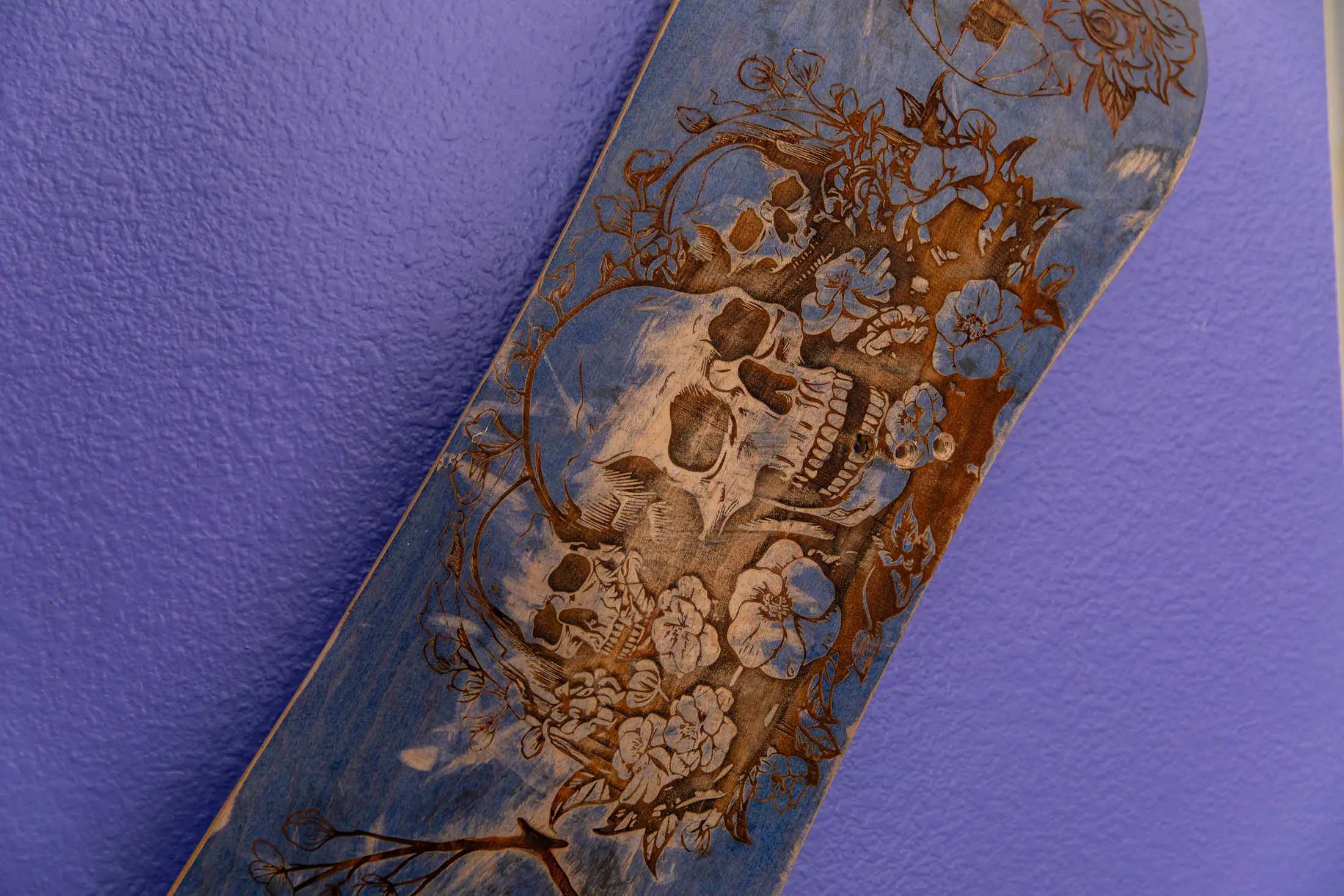 Skateboard with intricate skull and flowers design.